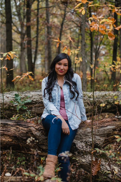 Erica Violet Lee sitting on a treestump.